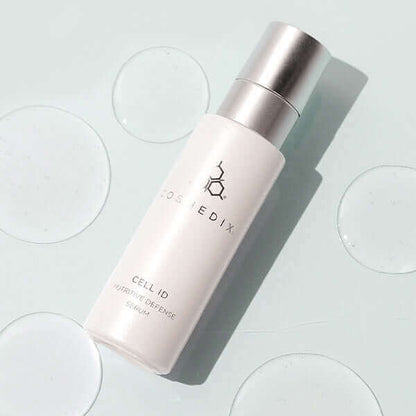 A bottle of Cell ID and drops of serum around it , it helps to reduce the signs of aging.