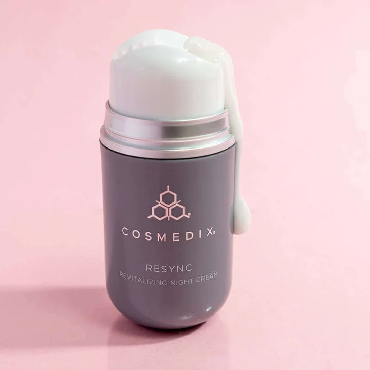 A bottle of Resync with product dripping down the side of the bottle. It is a revitalizing Night Cream with antioxidant-rich extracts—like Snow Mushroom and Kakudu Plum—that quench skin with long-lasting moisture to help restore radiance and revitalize the look of skin, all while you sleep.